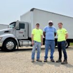 Three Redkey Express employees standing in front of one of their branded vehicles.
