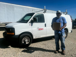 Redkey Express employee standing in front of branded van, holding a package.
