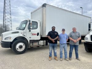 Three Redkey Express employees standing in front of one of their branded vehicles.