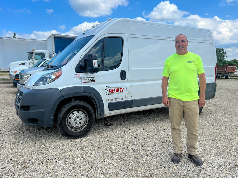 Redkey Express employee standing in front of one of their branded vehicles.